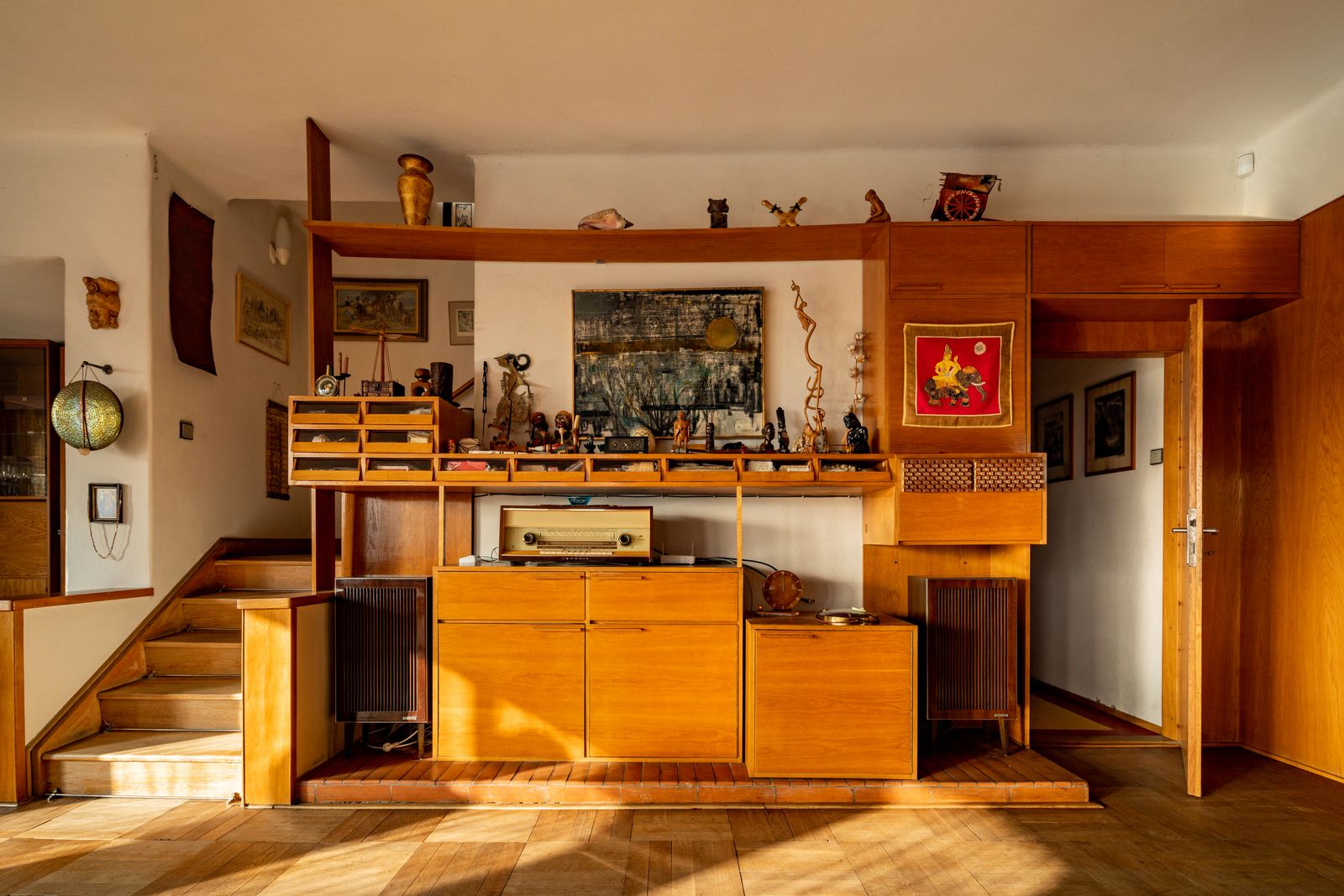 Souvenirs and mementos from Zikmunds travels are displayed on builtin wooden shelves drawers and cupboards