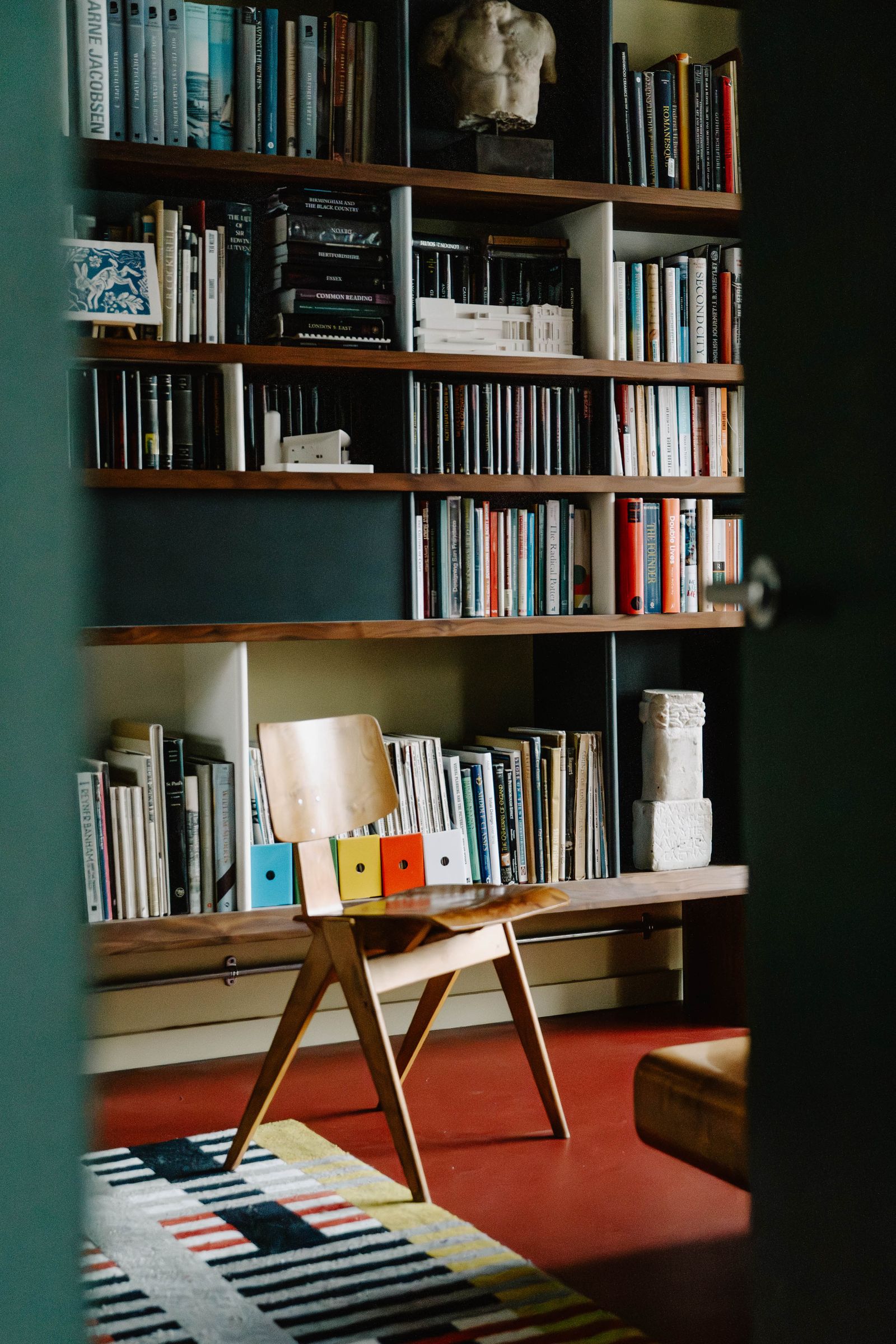 Image may contain Furniture Bookcase Home Decor Rug Chair and Person